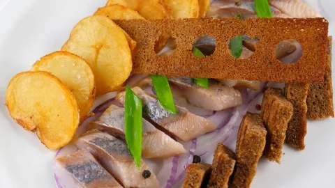 Sliced herring fish, decorated with crunchy rye bread, roast potato and onion Stock Footage 84263357