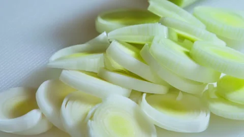 Sliced, leeks piled on a white kitchen board. Slow camera movement to the left. Stock Footage 303409432
