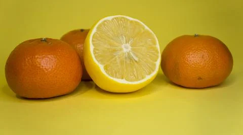Sliced lemon and tangerine, on a yellow background. Citrus fruits. Stock Photos