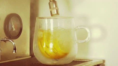Sliced lemon in a cup being filled with hot water from a commercial machine. Stock Footage 233586544