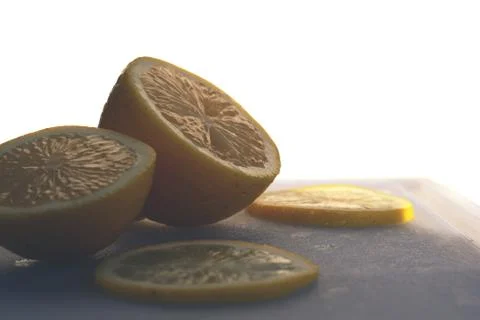 A sliced lemon on a cutting board against a bright background Photos