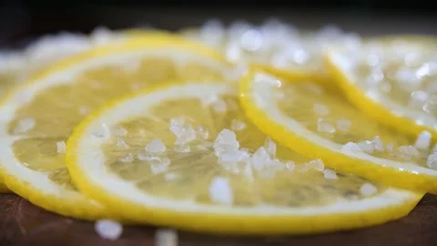 Sliced lemon sprinkled with coarse salt close-up. Background in blur. Stock Footage 155351515