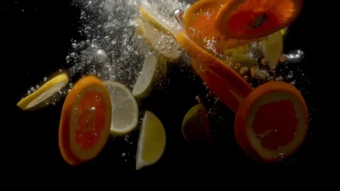 Sliced lemons and oranges falling into the water Stock Footage 123579329