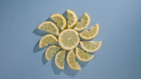Sliced lemons arranged in a sun pattern on a blue background, artistically Stock Footage 274814574