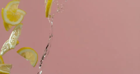 Sliced lemons fly through air as water falls in slow motion Video stock 249561241