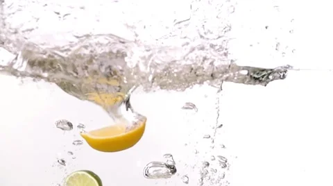 Sliced lime lemon fruits falling into water white slow motion HD video. Waves Stock Footage 68458490