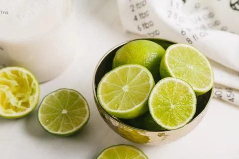 Sliced limes in a plate on a white table. Stock Photos