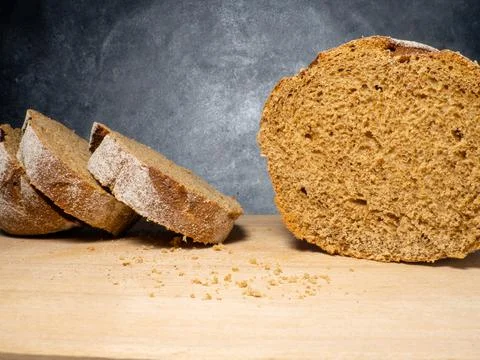 Sliced loaf of black bread on a kitchen board. Bread on a black background. H Stock Photos