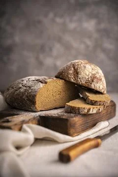 Sliced loaf of black bread on the old rustic wooden cutting board. Selective  Stock Photos