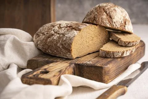 Sliced loaf of black bread on the old rustic wooden cutting board. Selective  Foto stock