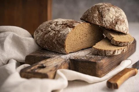 Sliced loaf of black bread on the old rustic wooden cutting board. Selective  Foto stock