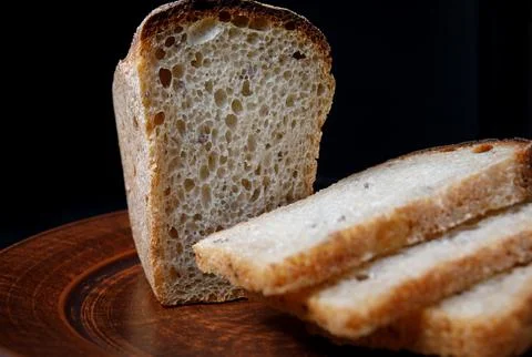 Sliced loaf of bread close-up on a ceramic plate. Sourdough bread. Stockfoto's