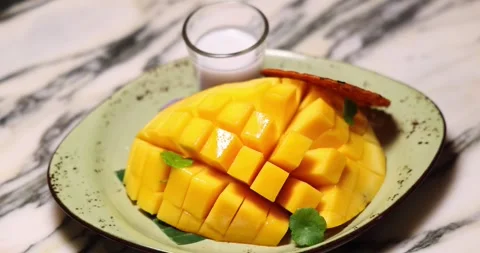 Sliced mango with coconut milk on ceramic plate, tropical dessert Stock Footage 318117438