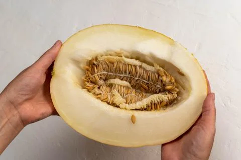 Sliced melon held in hands showing seeds and inner texture Фото