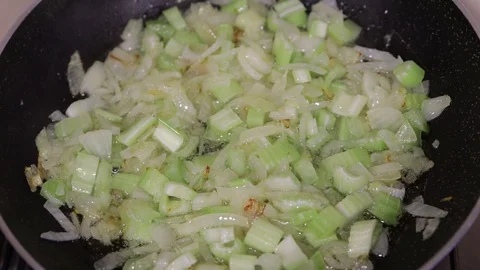 Sliced onion and celery in a frying pan Stock Footage
