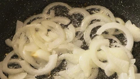 Sliced ??onion rings are fried in a frying pan with vegetable oil. Medium sho Stock Footage 340349736