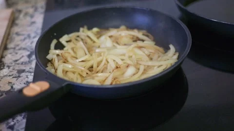 Sliced onions sizzling and caramelizing in a pan Stock Footage 335869795