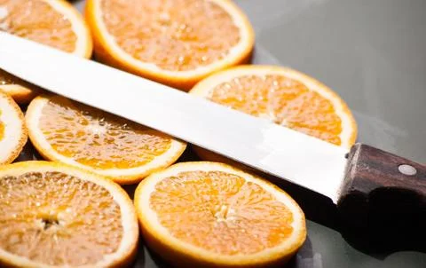 Sliced orange chunks with knife Stock Photos