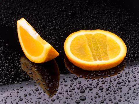Sliced orange fruit on black surface Stock Photos