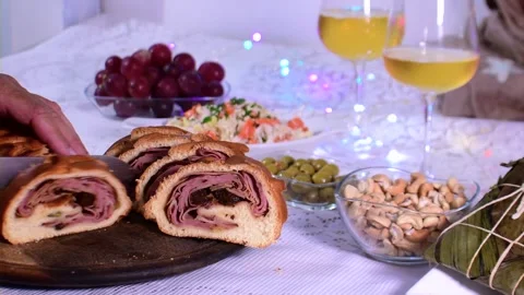 Sliced pan de jamon on a festive holiday table with hallaca and wine Видео 332686051