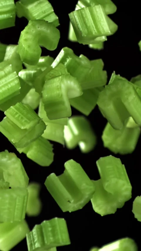 Sliced pieces of celery rise and fall on a black background. Filmed on a high Stock Footage 335372917