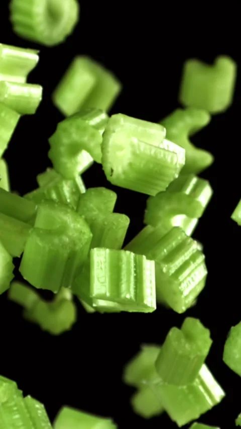 Sliced pieces of celery rise and fall on a black background. Filmed on a high Stock Footage 335376256