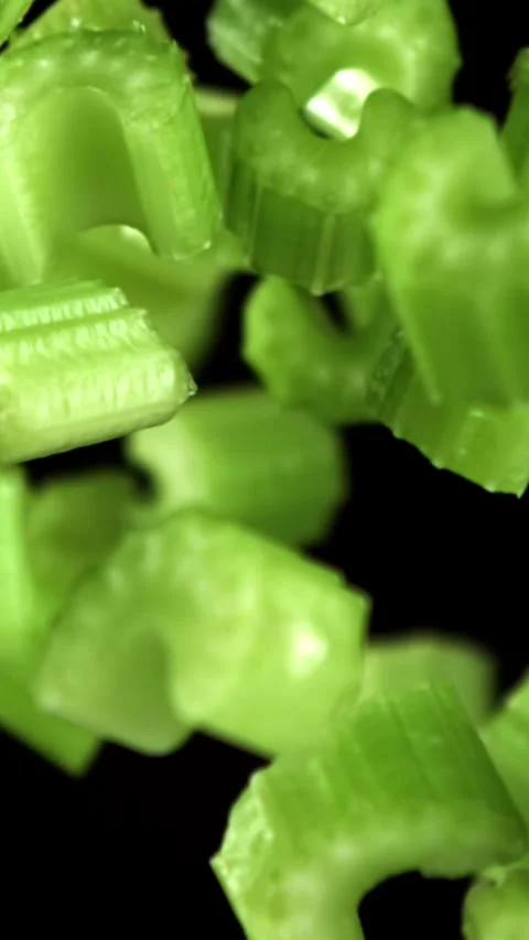 Sliced pieces of celery rise and fall on a black background. Filmed on a high Stock Footage 335379622