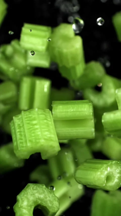 Sliced pieces of celery rise and fall on a black background. Filmed on a high Stock Footage 335380513
