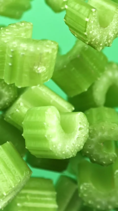 Sliced pieces of celery rise and fall on a green background. Filmed on a high Stock Footage 335384068