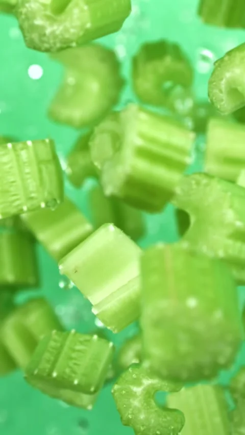 Sliced pieces of celery rise and fall on a green background. Filmed on a high Stock Footage 335384845