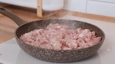Sliced pieces of chicken meat are fried in a frying pan with oil Stock Footage 318463566