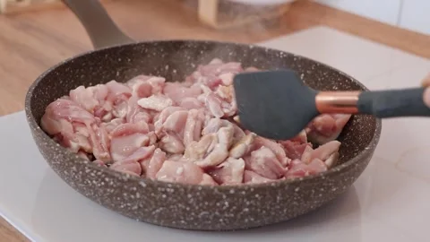 Sliced pieces of chicken meat are fried in a frying pan with oil Stock Footage 318463583