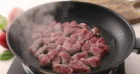 Sliced pieces of raw meat are fried in a frying pan. Stock Footage 250019964