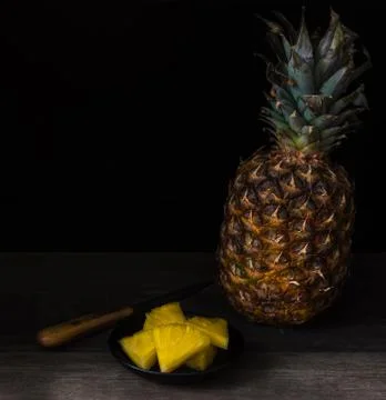Sliced pineapple on black isolated background on old rustic desk. Stock Photos