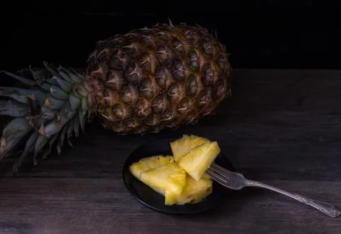 Sliced pineapple on black isolated background on old rustic desk. Stock Photos