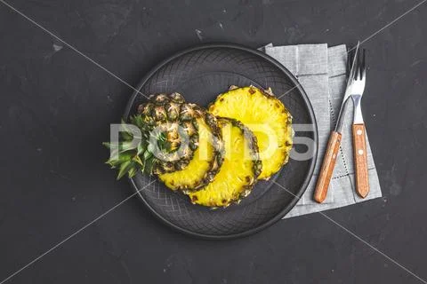 Sliced pineapple in ceramic plate and set of cutlery Stock Photos