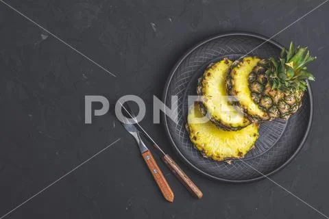 Sliced pineapple in ceramic plate and set of cutlery Stock Photos