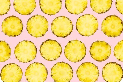 Sliced pineapple pieces lay in pattern on isolated light pink background Stock Photos