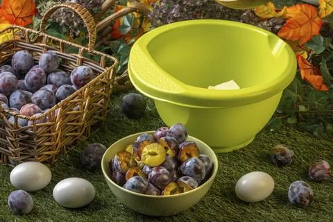 Sliced plums and eggs next to dough bowl in an autumn setting Stock Photos
