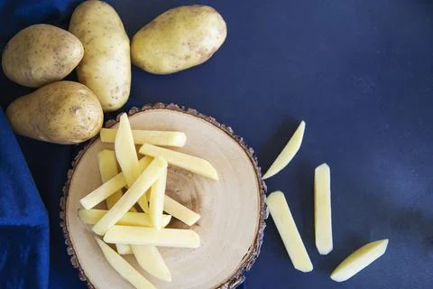 Sliced potato stick ready for making French fries - traditional food preparat Stock Photos