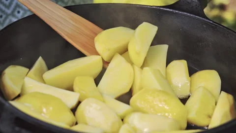 Sliced potatoes are being cooked in a cast iron pan outdoors on a grill. Stock Footage 315271273