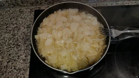 Sliced potatoes are fried in the pan with olive oil over the electric hob, Stock Footage 221883024