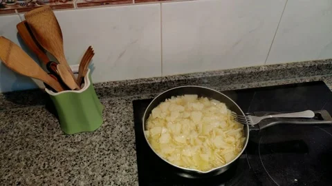 Sliced potatoes are fried in the pan with olive oil over the electric hob, Stock Footage 221883030