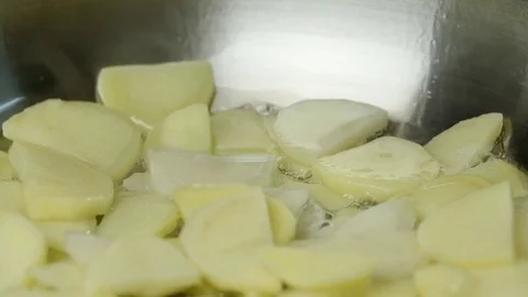 Sliced potatoes fried in a pan 4k сlose up video. Chopped chips on boiling oil Stock Footage 70198076