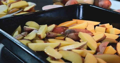 Sliced potatoes on an iron baking sheet are salted before baking Stock Footage 168816678