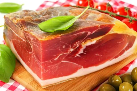 Sliced prosciutto ham with basil garnish Stock Photos