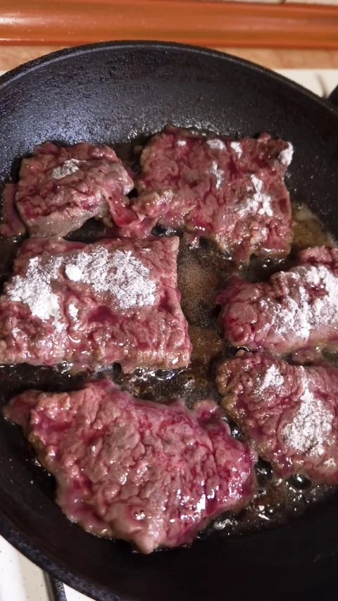 Sliced Raw Beef Liver Sizzling in Hot Oil Inside a Black Frying Pan Stock Footage 339080409