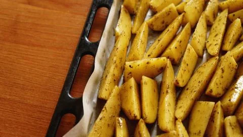 Sliced raw potatoes on a baking sheet with spices and rosemary, top view Stock Photos
