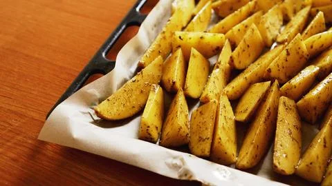 Sliced raw potatoes on a baking sheet with spices and rosemary, top view Stock Photos