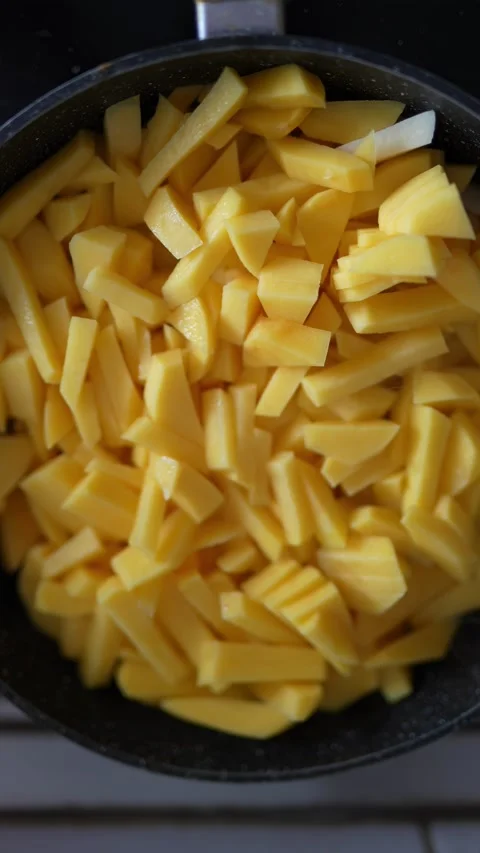 Sliced raw yellow potatoes are being cooked in a pan. Stock Footage 332160246